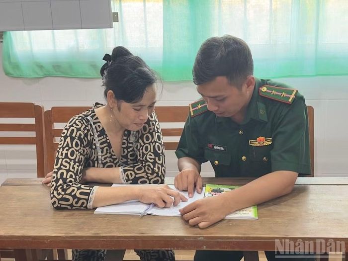 Trung úy Hồ Mộng Long hướng dẫn chị Dương Thúy Liễu cách đánh vần.