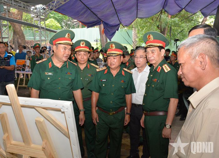 Đại tướng Phan Văn Giang xem các hình ảnh về quá trình tìm kiếm, quy tập hài cốt liệt sĩ tại Công viên Lê Thị Riêng. 