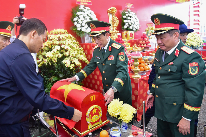  Đại tướng Phan Văn Giang và các đại biểu thực hiện nghi thức phủ Quốc kỳ lên quách chứa hài cốt anh hùng liệt sĩ. 