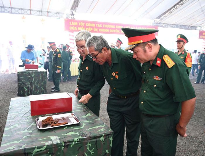  Các cựu chiến binh bên các di vật của liệt sĩ vừa được tìm thấy. Ảnh: XUÂN TRUNG 