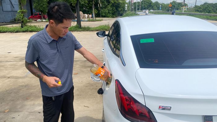  Một tài xế mua xăng lẻ trong chai để đổ vào bình nhiên liệu ô tô. Ảnh: PHÚC HẬU 