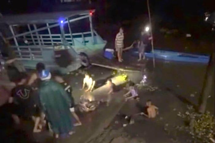 Lực lượng chức năng phối hợp cùng người dân đưa thi thể nạn nhân lên bờ. Ảnh cắt từ clip.