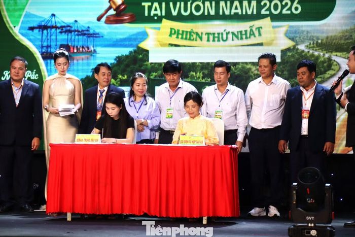 Đại diện doanh nghiệp trúng đấu giá (bên phải) và đại diện chủ vườn ký biên bản sau phiên đấu giá.