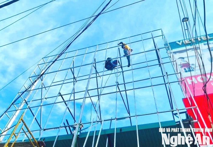 Thợ làm biển quảng cáo hàn khung trên cao. Ảnh tư liệu minh họa: Hải An