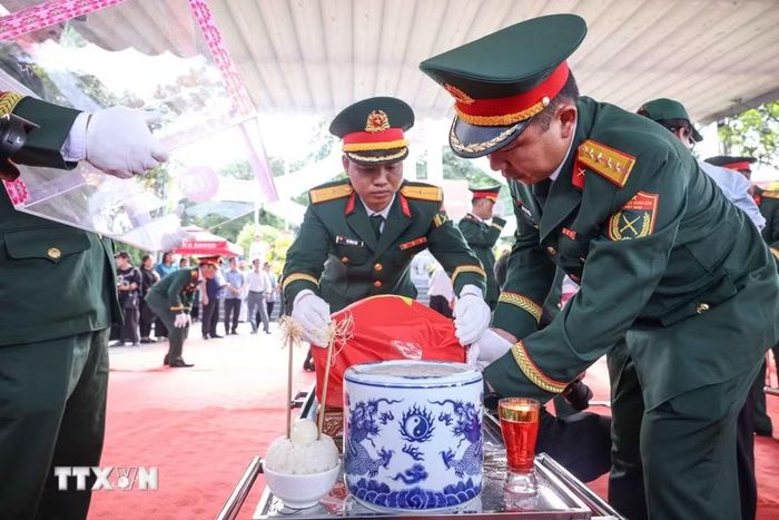 Thành viên Đội tìm kiếm, quy tập hài cốt liệt sỹ tỉnh Hà Giang với hài cốt các liệt sỹ mới được quy tập về Nghĩa trang liệt sỹ Quốc gia Vị Xuyên. (Ảnh: Hoàng Hiếu/TTXVN)