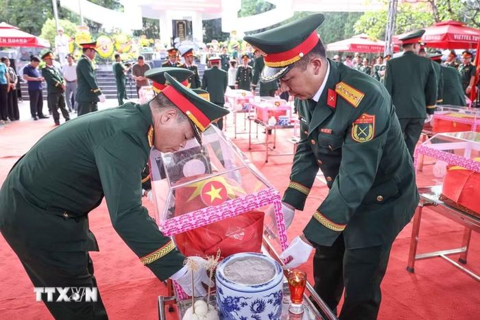 Thành viên Đội tìm kiếm, quy tập hài cốt liệt sỹ tỉnh Hà Giang với hài cốt các liệt sỹ mới được quy tập về Nghĩa trang liệt sỹ Quốc gia Vị Xuyên. (Ảnh: Hoàng Hiếu/TTXVN)