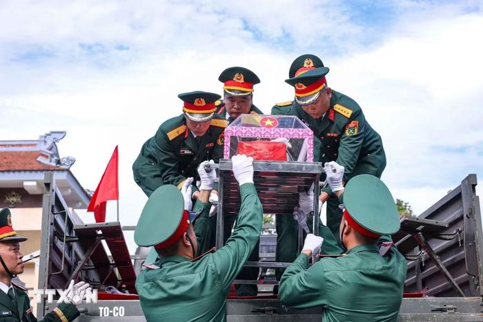 Di chuyển hài cốt liệt sỹ từ xe xuống Nghĩa trang liệt sỹ Quốc gia Vị Xuyên. (Ảnh: Hoàng Hiếu/TTXVN)