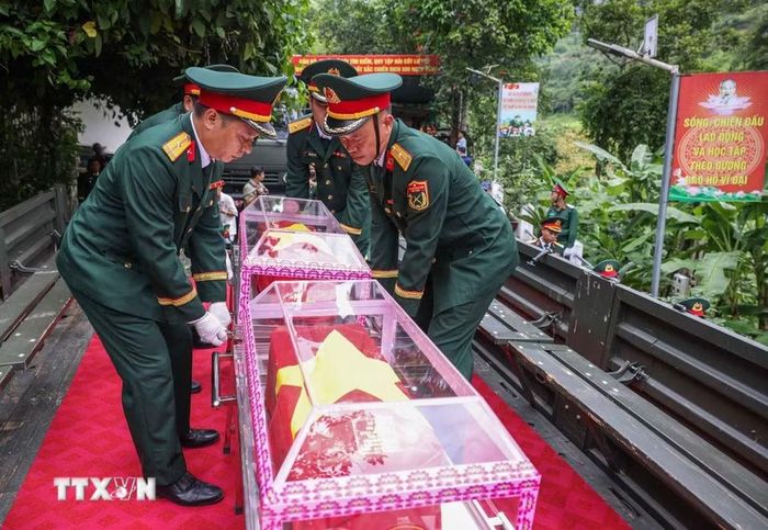 Đưa hài cốt 34 liệt sỹ di từ nhà chờ Đội tìm kiếm, quy tập hài cốt liệt sỹ tỉnh Tuyên Quang lên xe để di chuyển về Nghĩa trang liệt sỹ Quốc gia Vị Xuyên. (Ảnh: Hoàng Hiếu/TTXVN)