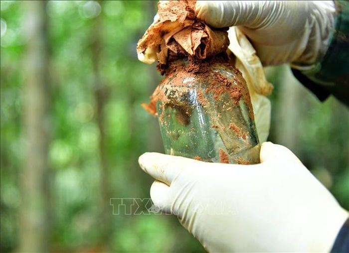 Lọ thủy tinh có chứa giấy nghi có thông tin được an táng kèm hài cốt liệt sĩ. Ảnh: TTXVN phát