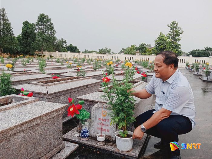 Ông Nguyễn Phước Sơn, Bí thư Đảng ủy, Chủ tịch HĐND xã Quế Sơn Trung đặt chậu hoa vạn thọ tại phần mộ liệt sĩ. Ảnh: DUY THÁI