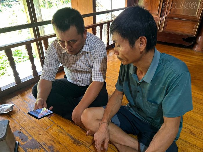 Cán bộ Trung tâm Dịch vụ tổng hợp xã Bảo Ái hướng dẫn người dân tiếp cận thông tin, chính sách giảm nghèo qua điện thoại thông minh.