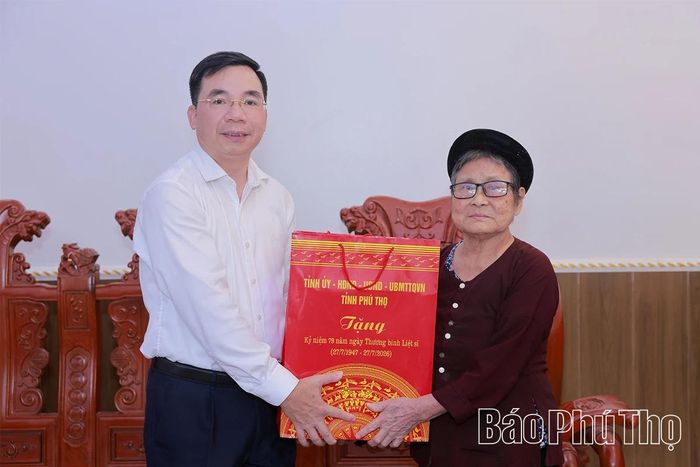 Đồng chí Phó Bí thư Tỉnh ủy Bùi Huy Vĩnh trao quà tặng bà Lưu Thị Bính.