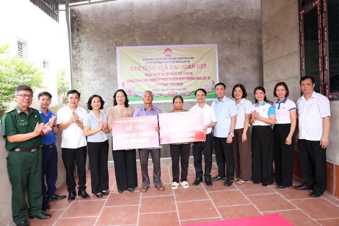 Phó Chủ tịch Ủy ban MTTQ Việt Nam TP Hà Nội Nguyễn Thị Thu Huyền (thứ 5 từ trái sang) và lãnh đạo xã Bất Bạt trao kinh phí hỗ trợ các gia đình. Ảnh: Trí Nhân.