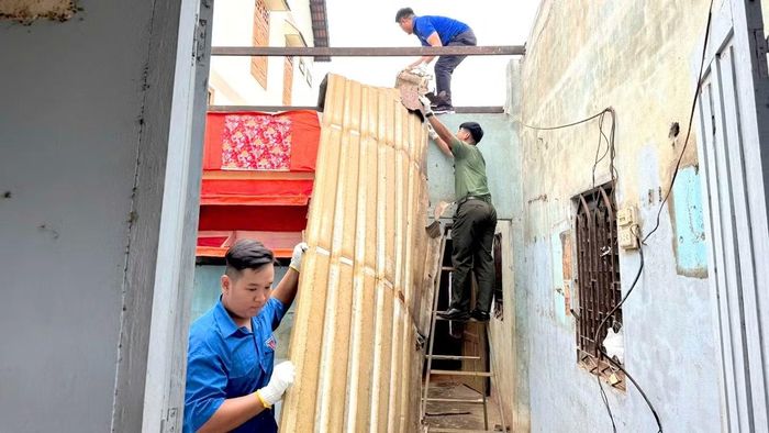 Đoàn viên thanh niên Công an xã Bom Bo cùng đoàn thanh niên xã tháo tôn cũ để sửa nhà cho gia đình bà Nông Thị Nhói thờ cúng Liệt sĩ.