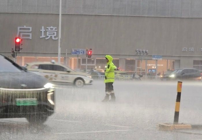 Cảnh sát điều tiết giao thông dưới cơn mưa trắng trời ở Thượng Hải, ngày 19/7. (Ảnh: Shangguan)