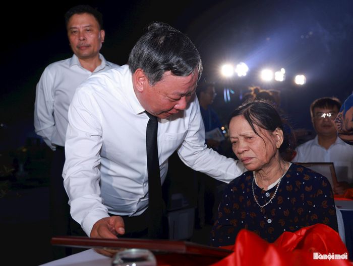 Phó Bí thư Thành ủy Hà Nội Nguyễn Văn Phong trao di ảnh được phục dựng và động viên thân nhân liệt sĩ. Ảnh: Văn Tuyến.