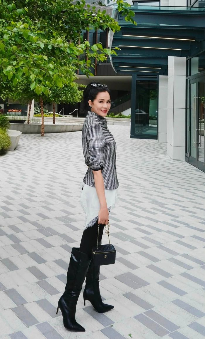 Ở một khung cảnh khác, Dạ Thảo diện áo hai dây lụa phối ren trắng, khoác sơ mi kẻ sọc, kết hợp quần skinny jeans đen và boots cao cổ dạo phố. Chiếc Chanel Pearl Crush Gold Ball Vanity bằng da bê màu đen, theo The Luxury Closet - nền tảng giao dịch hàng hiệu quốc tế, mẫu túi có giá khoảng 6.300 USD, tương đương hơn 165 triệu đồng.