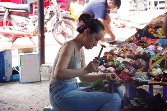 Chị Mai Thanh cặm cụi đóng guốc cho khách. Ảnh: Kim Cương