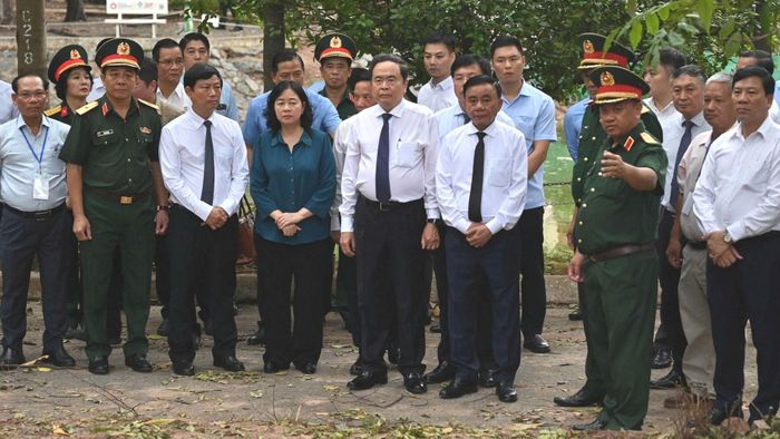 Đoàn công tác nghe báo cáo về quá trình tìm kiếm, khai quật hài cốt liệt sĩ. Ảnh: MẠNH THẮNG