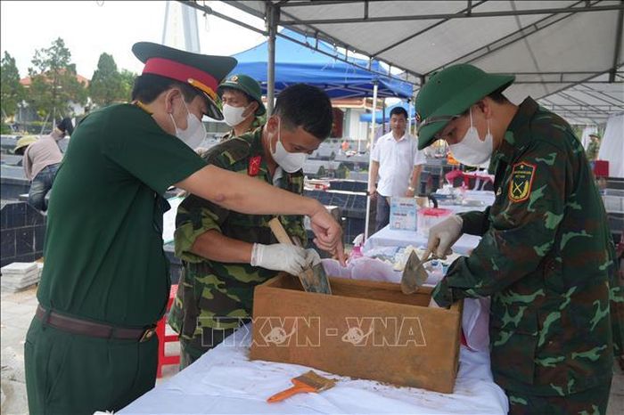 Đại tá Nguyễn Xuân Toàn, Phó Chính ủy Bộ Chỉ huy Quân sự tỉnh Thanh Hóa (ngoài cùng bên trái) trực tiếp kiểm tra, chỉ đạo công tác lấy và bàn giao mẫu tại Nghĩa trang Liệt sĩ Hoằng Hóa. Ảnh: Khiếu Tư/TTXVN