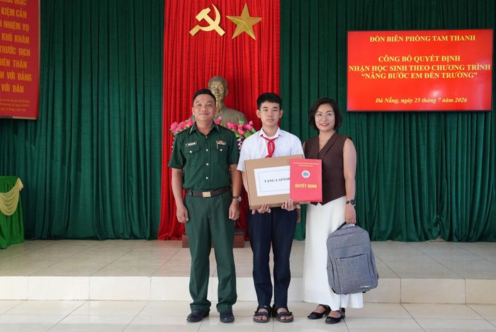 Chỉ huy Đồn Biên phòng Tam Thanh BĐBP thành phố Đà Nẵng và nhà hảo tâm trao Quyết định nhận đỡ đầu theo Chương trình "Nâng bước em tới trường" và quà cho em Trần Quang Hiếu. Ảnh: HUỲNH CHÍN
