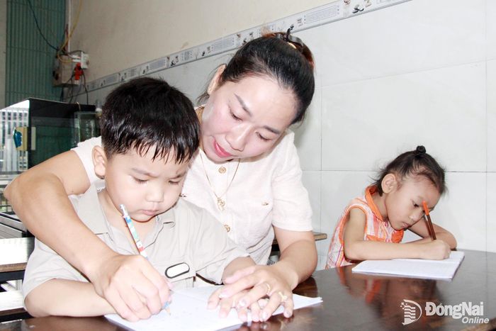 Chị Hồ Thị Thoa cầm tay dạy học sinh viết từng con chữ.