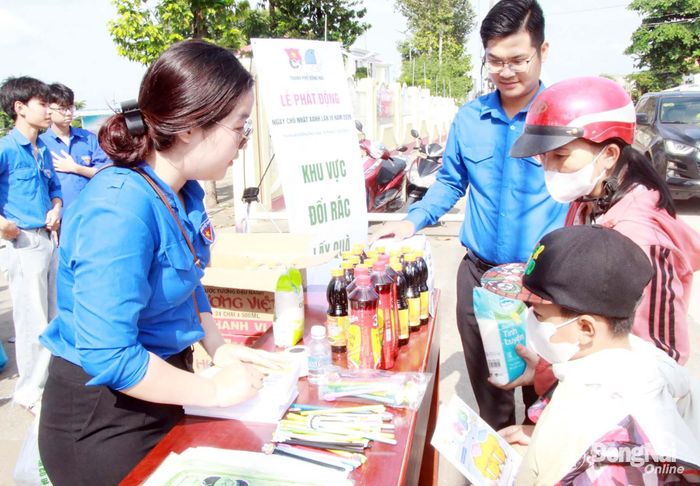 Đoàn viên, thanh niên hỗ trợ người dân và thiếu nhi khi tham gia đổi rác lấy quà. Ảnh: Nga Sơn