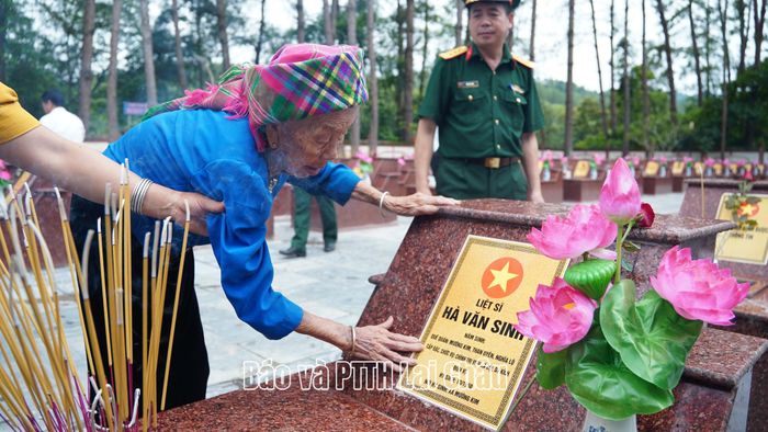 Bà Hà Thị È – con đẻ liệt sĩ Hà Văn Sinh xúc động trước phần mộ của cha tại nghĩa trang Than Uyên. 