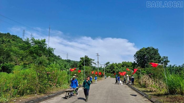 Các lực lượng lắp đặt hệ thống cột cờ và treo cờ Tổ quốc đồng bộ trên tuyến đường dài 400 m tại thôn Long Khánh.