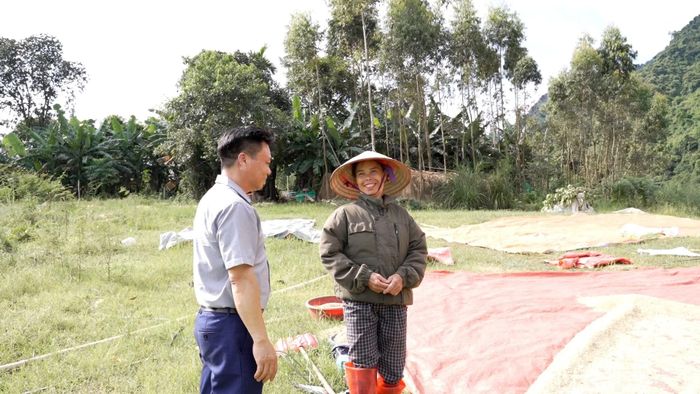Cán bộ địa phương trao đổi với người dân về hiệu quả sản xuất lúa trên diện tích đất tận dụng khi nước hồ rút tại xã Tân Lĩnh.