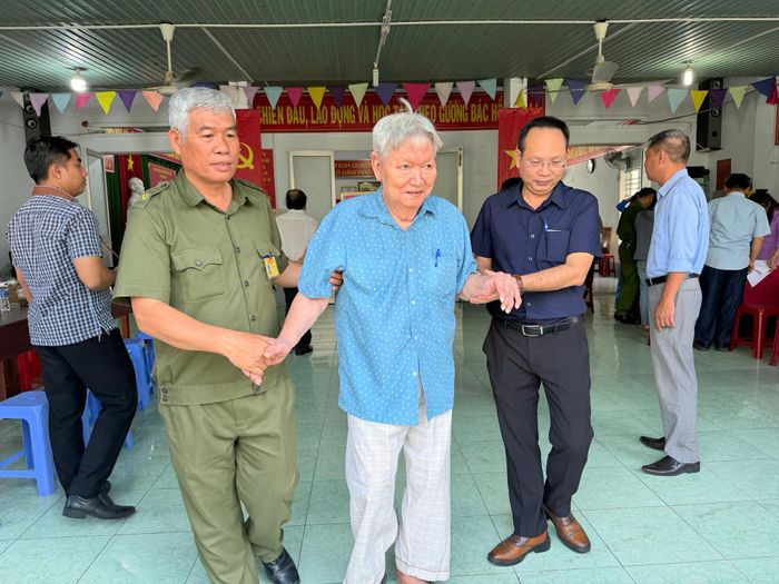 Một cán bộ hưu trí được người nhà hỗ trợ đến nơi bỏ phiếu thực hiện quyền cử tri tại một điểm bỏ phiếu tại phường Phú Thủy