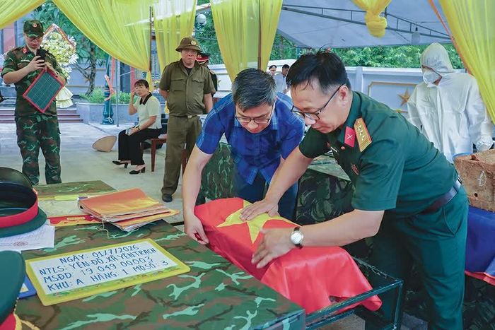 Hài cốt liệt sĩ được cẩn trọng chuyển sang tiểu quách mới, phủ Quốc kỳ trước khi hoàn mộ.