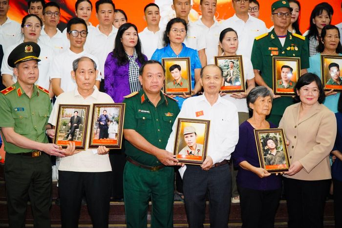 Phó Bí thư Thành ủy Văn Thị Bạch Tuyết, Chính ủy Bộ Tư lệnh thành phố, Thiếu tướng Nguyễn Thành Trung, cùng các đại biểu tặng di ảnh đã được phục chế cho thân nhân gia đình liệt sĩ. Ảnh: Hoa Lê