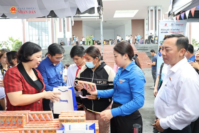 Các đại biểu hỗ trợ các em học sinh nhận quà theo phiếu mua hàng tại Phiên chợ 0 đồng