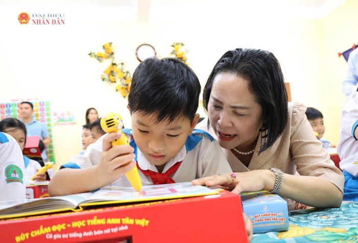 Phó Chủ tịch Quốc hội Nguyễn Thị Thanh hướng dẫn các em học sinh sử dụng sách kèm bút chấm đọc học tiếng Anh