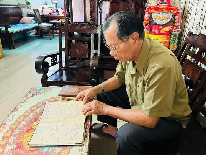 Bác sĩ Trần Văn Bản xúc động giở cuốn sổ ghi chép thông tin các liệt sĩ. Ảnh: H.Phương