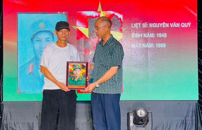 Ông Phạm Anh Tuấn - Phó chủ tịch UBND xã Chí Minh trao bức ảnh phục dựng cho thân nhân liệt sĩ Nguyễn Văn Quý. Ảnh: Nguyễn Ngân.