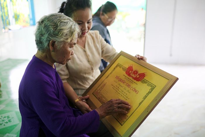  Bà Lệ nâng niu tấm bằng Tổ quốc ghi công của liệt sĩ Huỳnh Văn Quên. Bà từng lưu giữ những lá thư người thương gửi về từ chiến trường, nhưng sau một mùa mưa bão, tất cả đã không còn nguyên vẹn. Ảnh: Quỳnh Danh. 