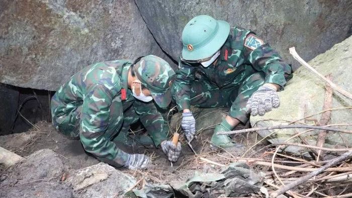 Bộ đội cẩn trọng lật từng phiến đá dưới hang sâu.