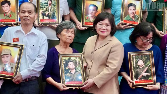 Ông Nguyễn Văn Đức (áo trắng) nhận di ảnh anh trai liệt sĩ từ bà Văn Thị Bạch Tuyết, Phó Bí thư Thành ủy Thành phố Hồ Chí Minh trao tặng.