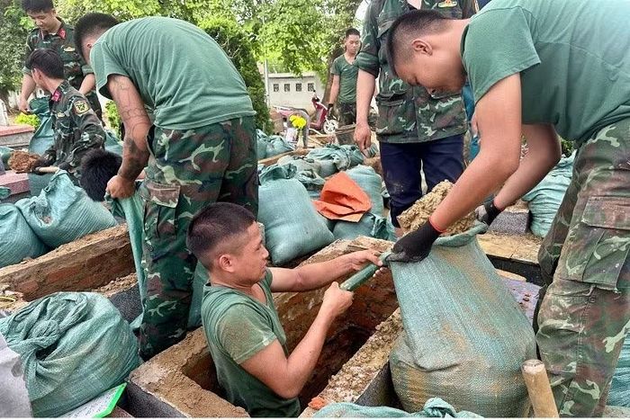 Các chiến sĩ làm nhiệm vụ khai quật, tìm mẫu ở Nghĩa trang liệt sĩ Độc Lập ướt đầm mồ hôi trong thời tiết nóng ẩm, mưa tầm tã.