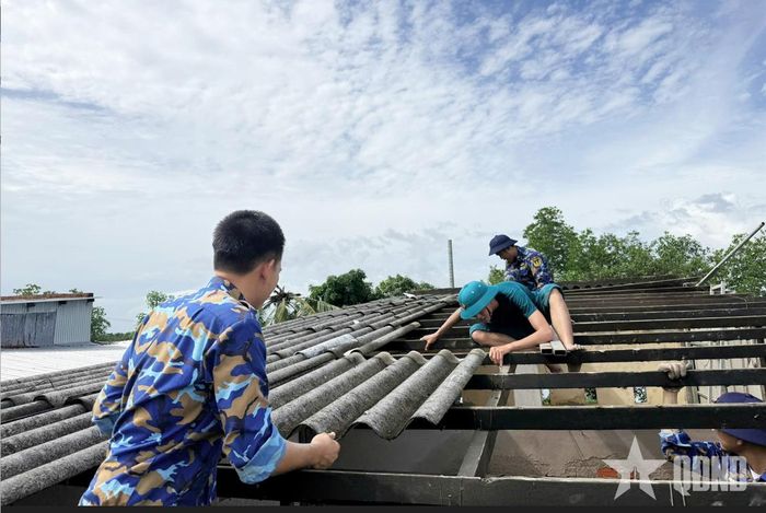 Cán bộ, chiến sĩ Lữ đoàn 175 cùng các lực lượng tháo dỡ phần mái nhà bị hư hỏng do dông lốc.