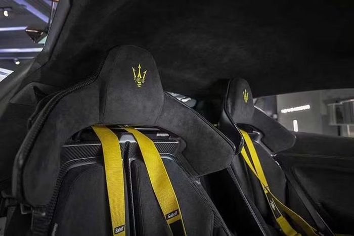 Khoang nội thất của Maserati GT2 Stradale Tribute to MC12 sử dụng ghế thể thao bọc Alcantara màu đen với logo cây đinh ba màu vàng trên tựa đầu, kết hợp dây đai an toàn xe đua bốn điểm thuộc gói Performance Plus.