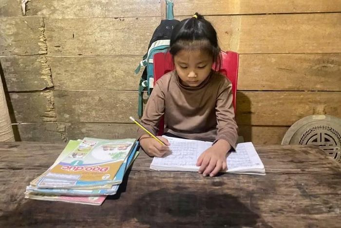 Trong căn nhà xập xệ, bé Diệu Linh lặng lẽ viết những dòng chữ gửi cho mẹ.