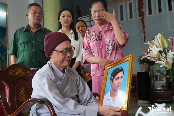 Bà Thủy (lau nước mắt) cùng gia đình nghẹn ngào bên di ảnh liệt sĩ Nguyễn Vũ Phát. Ảnh: Hoàng Anh