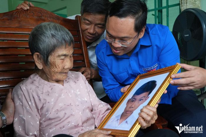 Mẹ Việt Nam Anh hùng Hồ Thị Vàng ngắm ảnh phục dựng con trai là liệt sĩ Nguyễn Văn Dậy. Ảnh: Hoàng Anh
