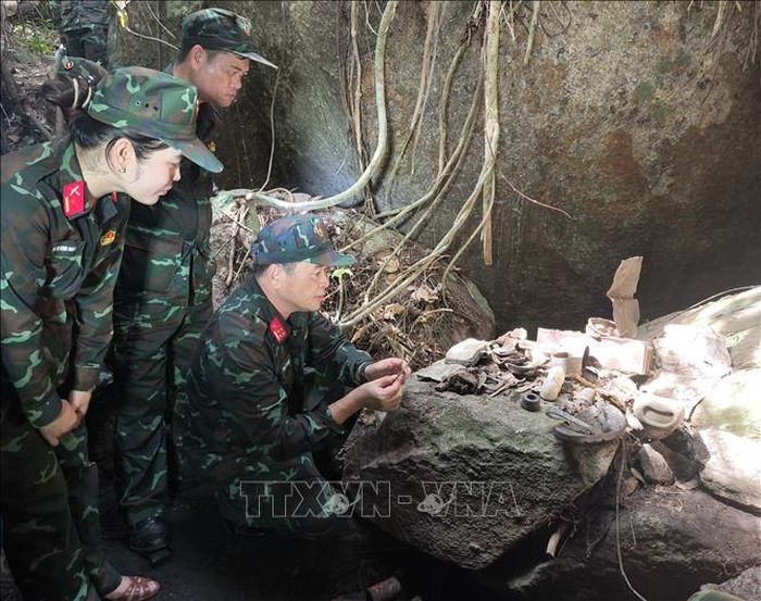 Đại tá Đinh Văn Hưng, Chính ủy Bộ Chỉ huy Quân sự thành phố Đà Nẵng (ngồi phía trước) xem di vật của các liệt sĩ trong hang Đá Sập. Ảnh: Quốc Dũng/TTXVN