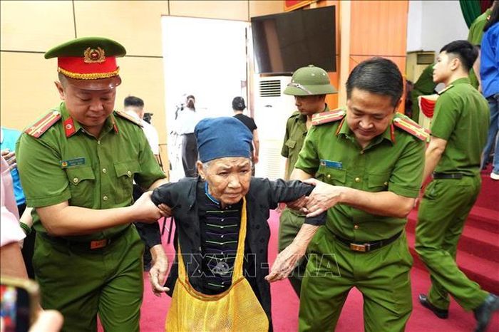 Cán bộ, chiến sĩ Công an tỉnh Tuyên Quang hỗ trợ thân nhân liệt sĩ tuổi cao đến điểm thu nhận mẫu sinh phẩm ADN. Ảnh: TTXVN phát