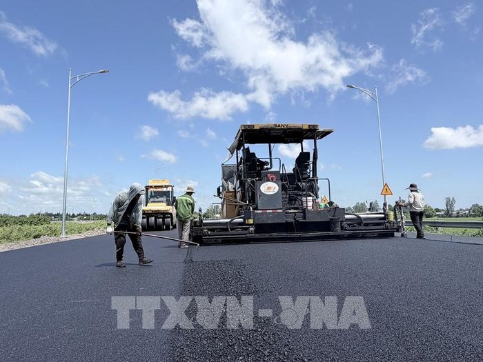 Nhà thầu đẩy nhanh thi công thảm nhựa đường dẫn vào tuyến cao tốc Châu Đốc - Cần Thơ - Sóc Trăng tại phường Vĩnh Tế, tỉnh An Giang. Ảnh: Thanh Sang - TTXVN