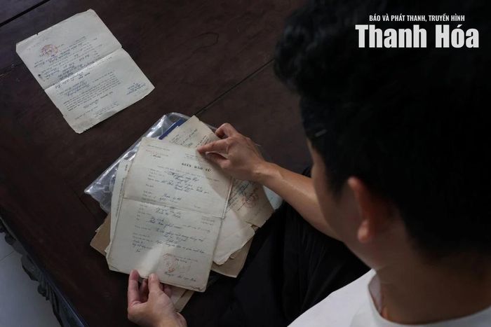 Anh Nguyễn Văn Vinh, con trai út của ông Tự mở lại giấy báo tử và những hồ sơ quân nhân đã được gia đình gìn giữ qua nhiều năm.